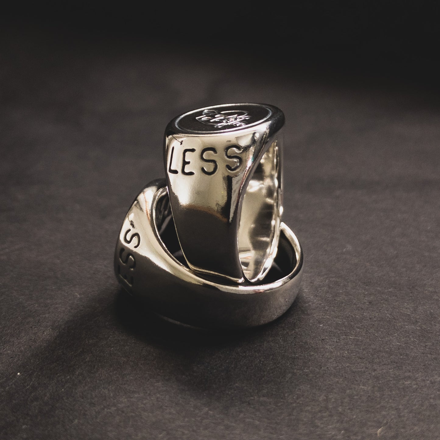 Two sterling silver signet rings with a polished finish, featuring a graphic of a heart with a knife through it. The rings are carved with the word "hopeless".